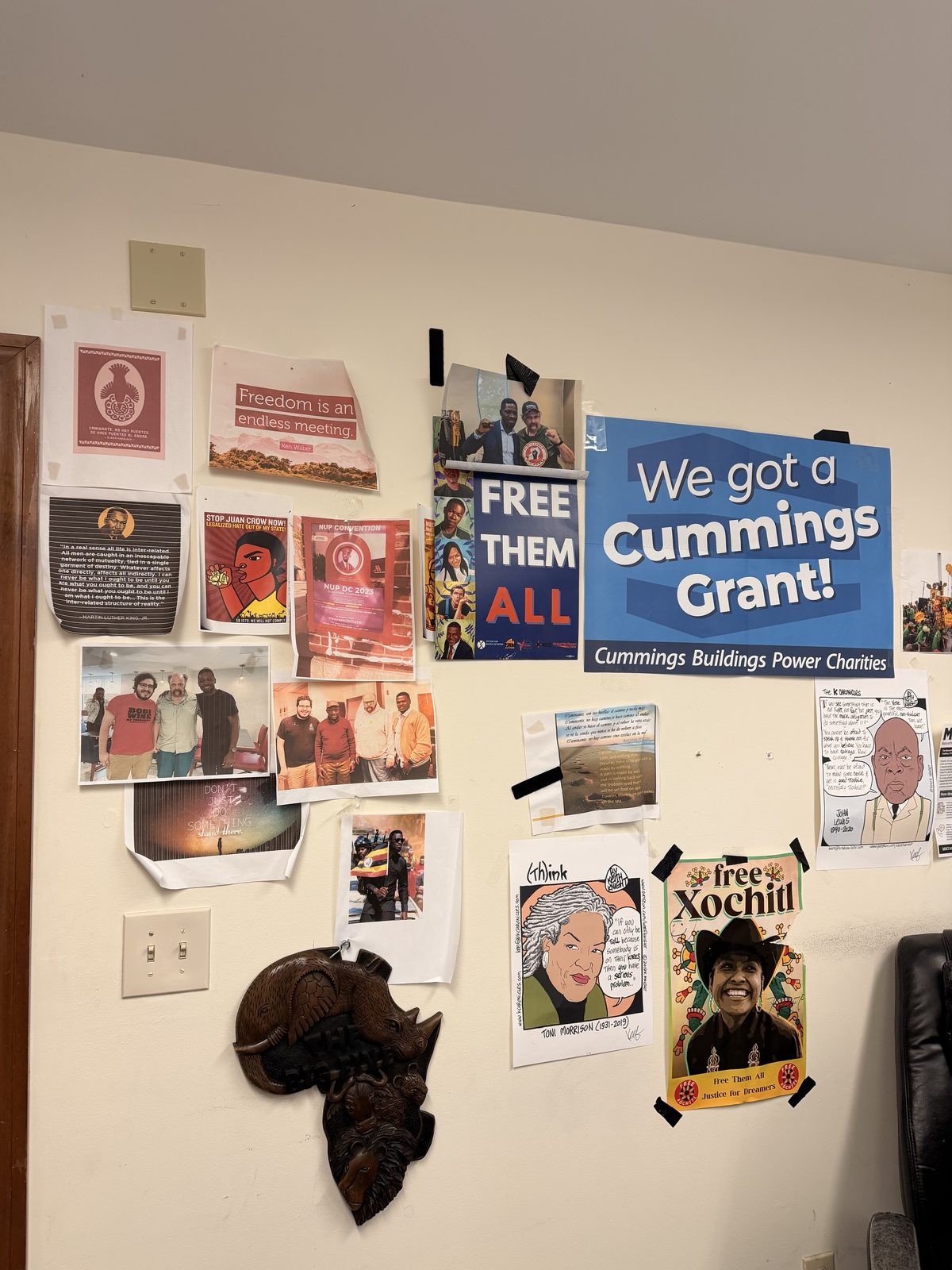 A wall in the TRII office covered with advocacy posters, art, and community photographs