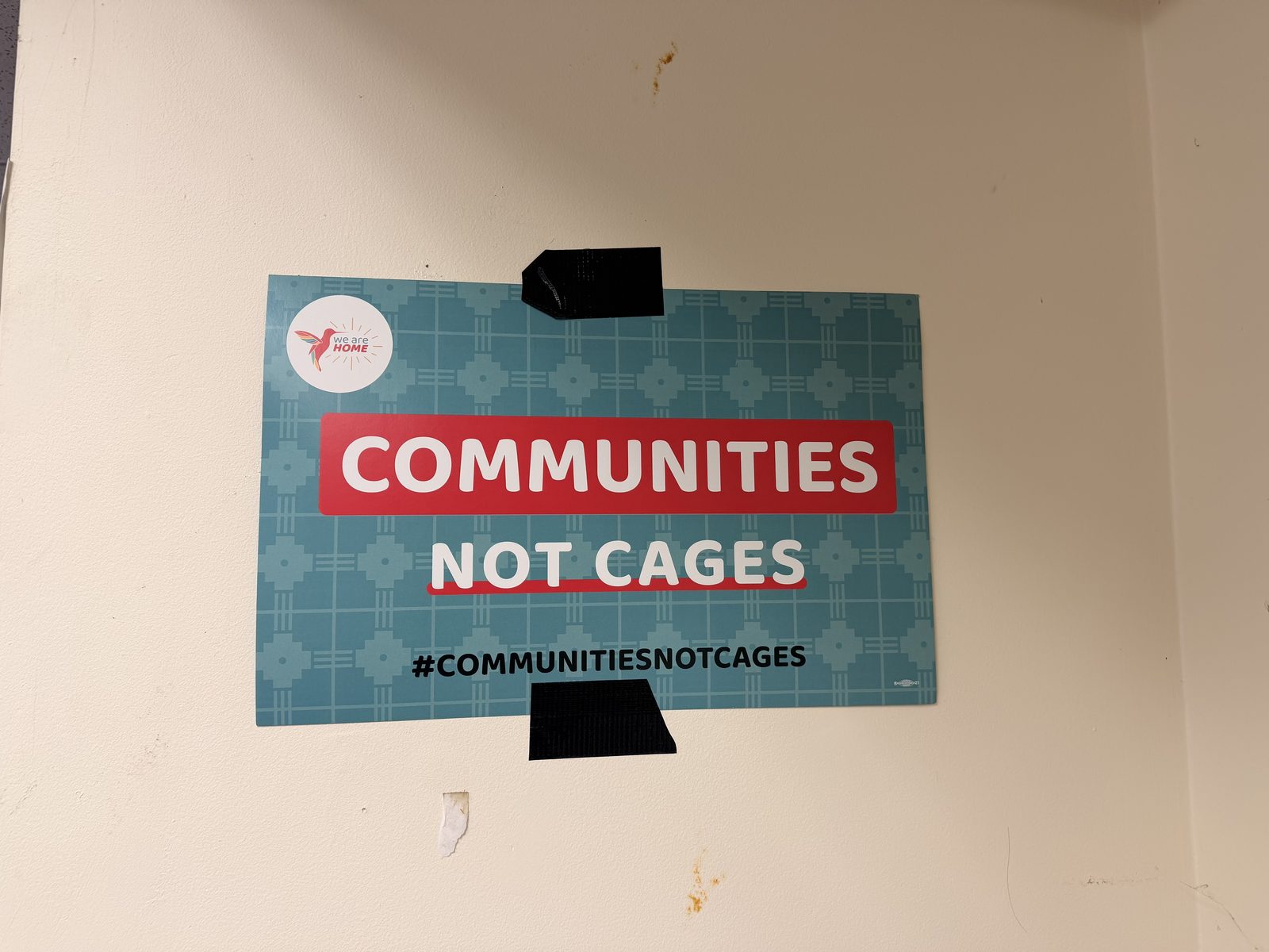 A Communities Not Cages poster on an interior wall